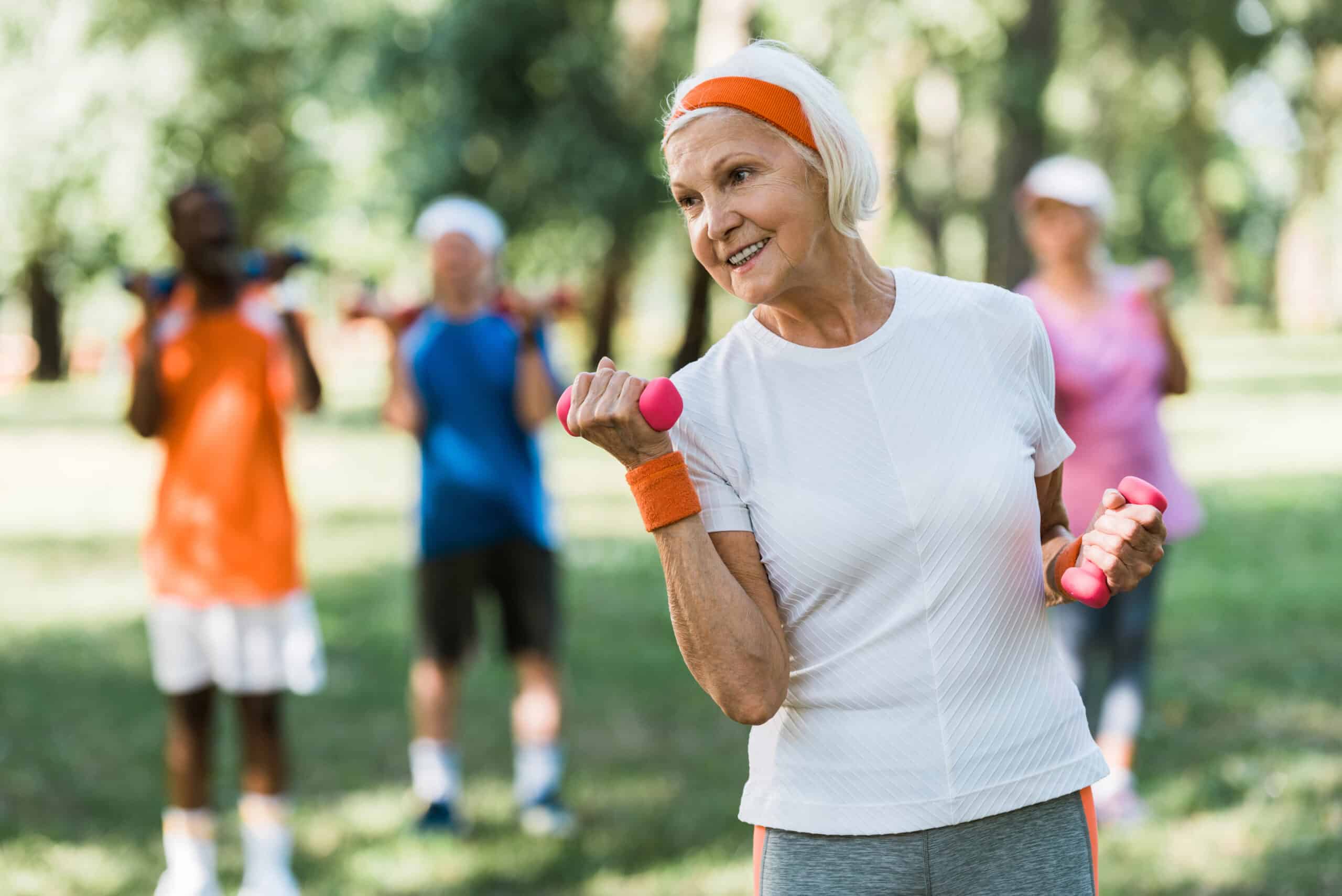 senior lady exercising outdoors with dumbbells