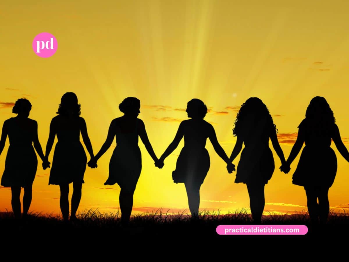 silhouette of women holding hands walking into sunset